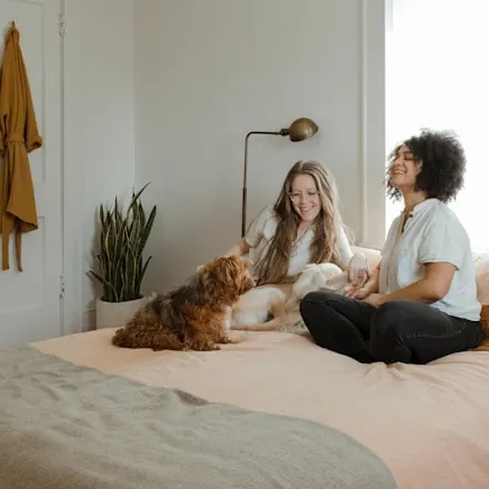 Woman sitting on a bed beside a brown dog