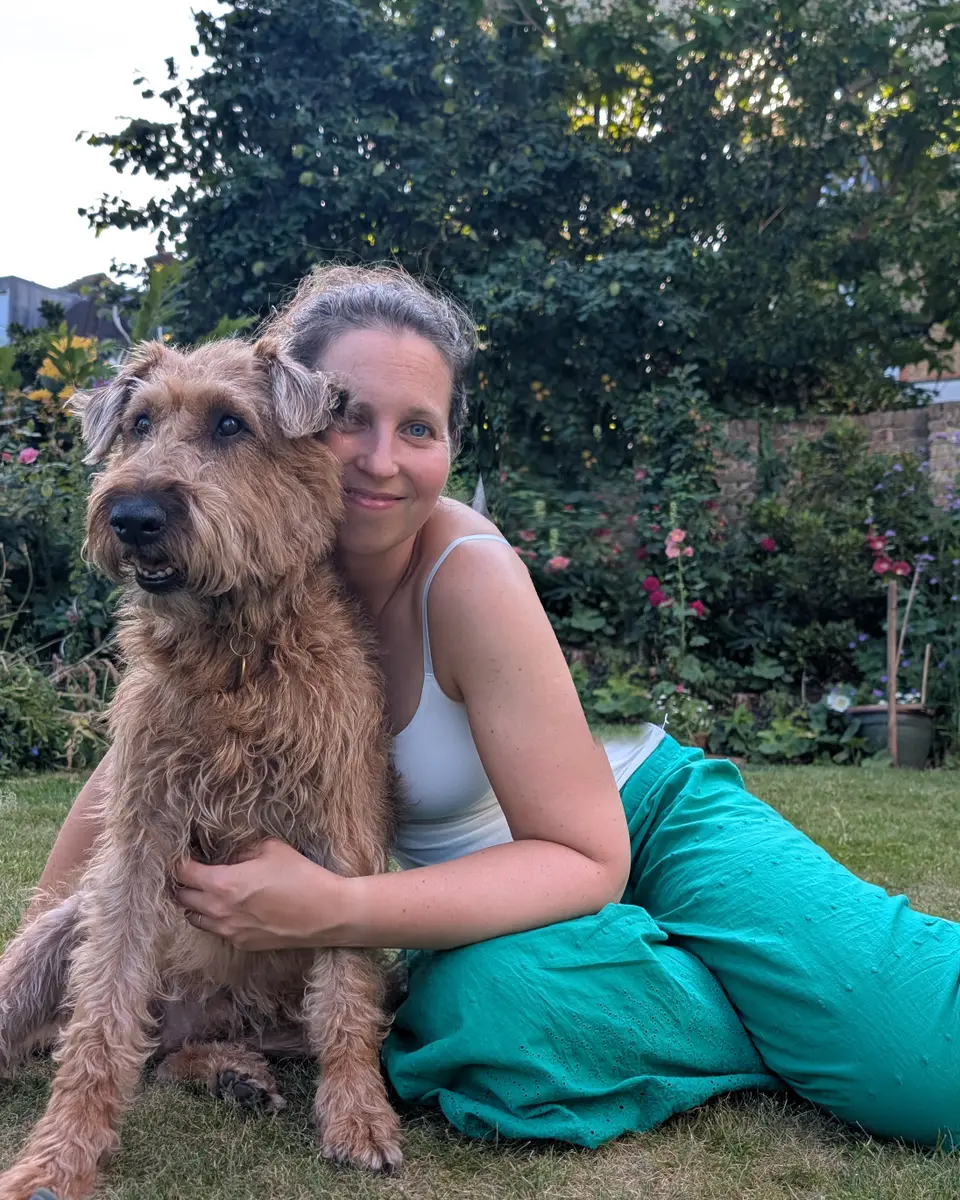 Alice sitting on the grass with her arm around her dog Riley